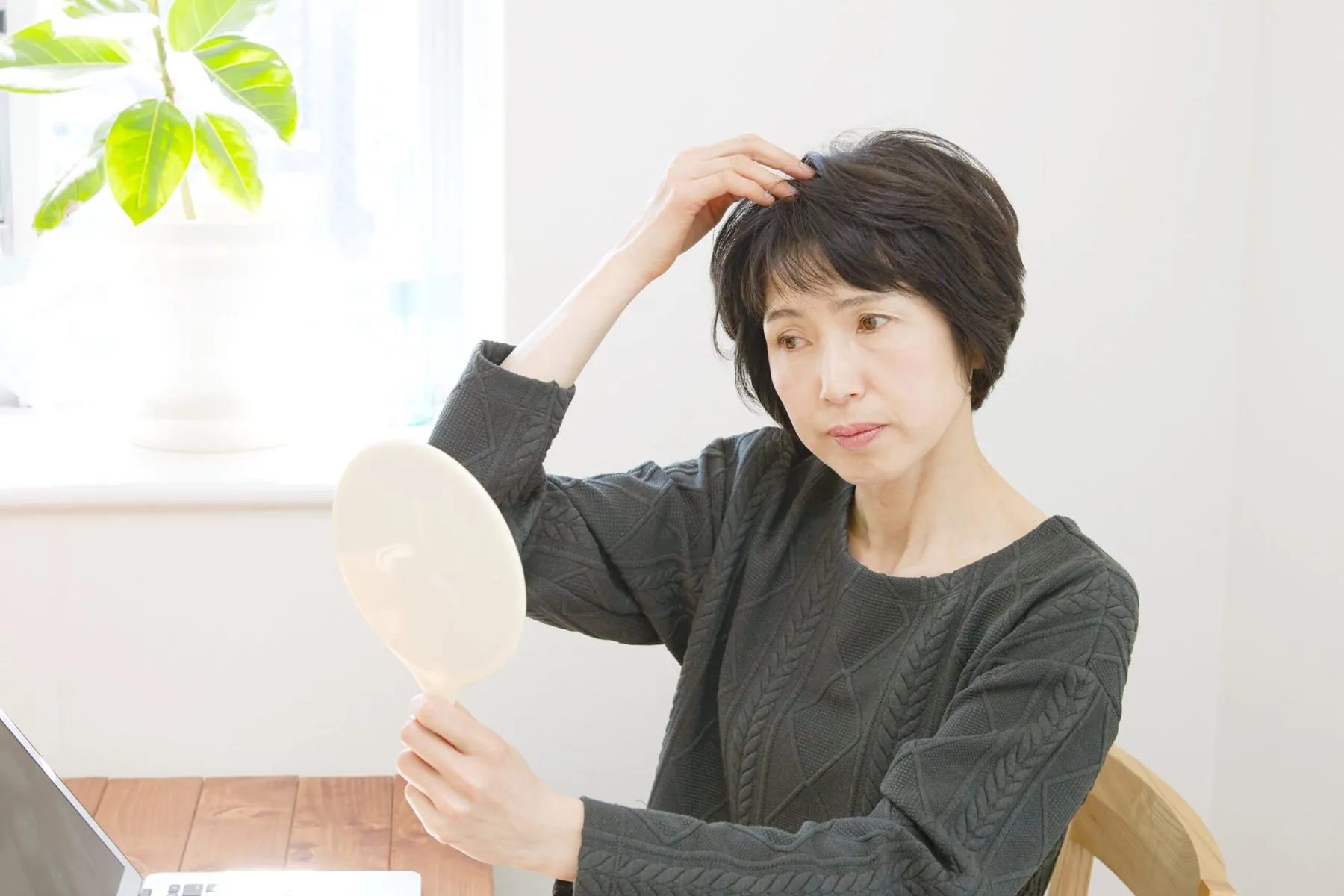 鏡で髪を気にする女性